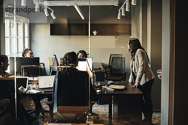 Unternehmerinnen bei einer Geschäftsbesprechung im Büro durch eine Glaswand gesehen