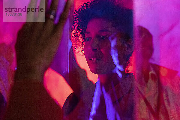 Unternehmerin bei der Untersuchung eines Glasdisplays während einer Firmenveranstaltung in einer beleuchteten Werkstatt