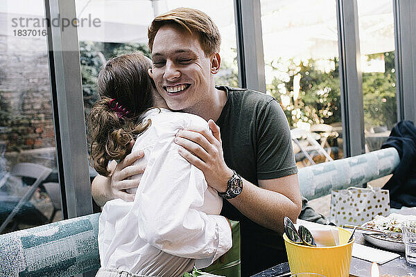 Glücklicher Mann umarmt Schwester im Restaurant
