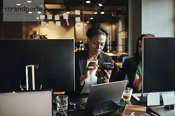 Geschäftsfrau  die im Büro mit ihrem Smartphone im Internet surft