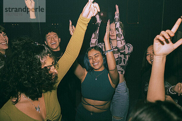 Fröhliche junge Freunde tanzen und amüsieren sich gemeinsam in einem Nachtclub
