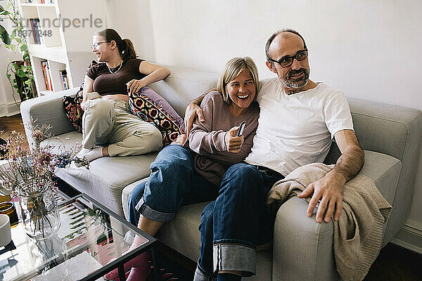Mann sitzt mit Frau und Tochter zu Hause auf dem Sofa