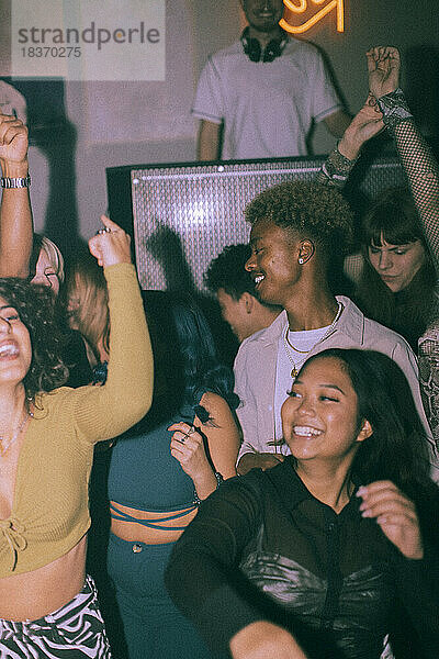 Fröhliche junge multirassische Männer und Frauen tanzen in einem Nachtclub