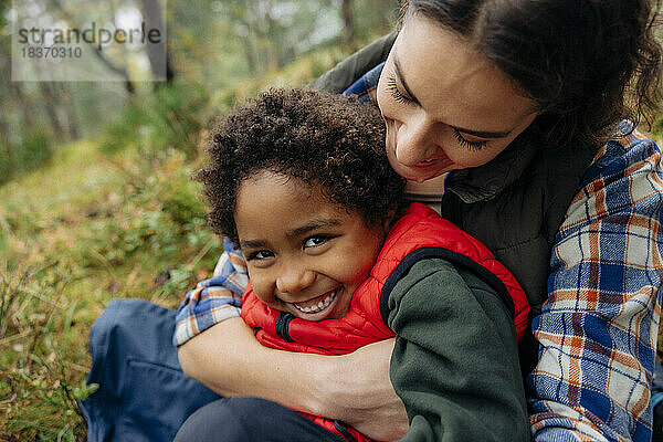 Mutter umarmt glücklichen Sohn im Wald