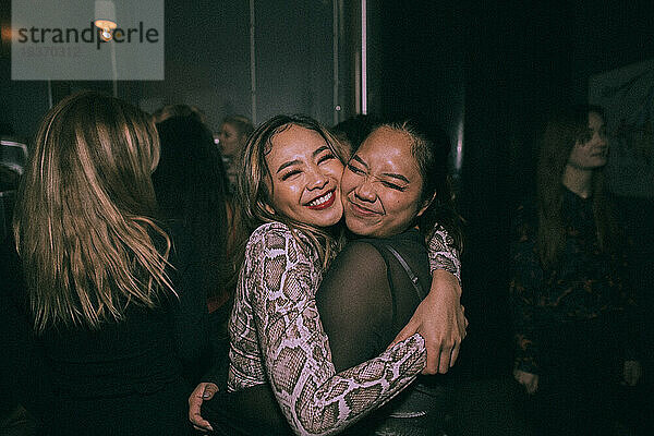 Fröhliche junge Frauen  die sich umarmen  während sie sich in einem Nachtclub vergnügen
