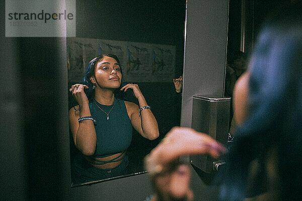 Spiegelbild einer jungen Frau  die sich im Badezimmer eines Nachtclubs im Spiegel spiegelt