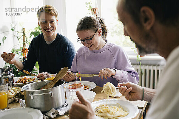 Glückliche Familie genießt das gemeinsame Essen am Esstisch zu Hause