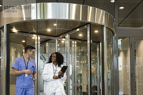 Lächelnde multirassische Ärzte und Ärztinnen vor einer Drehtür