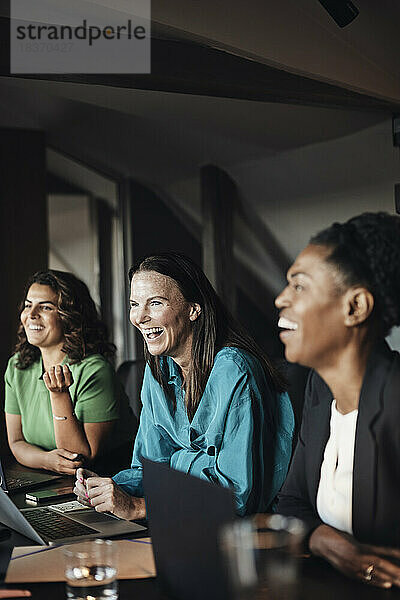 Lachende Unternehmerinnen bei einem Geschäftstreffen im Büro