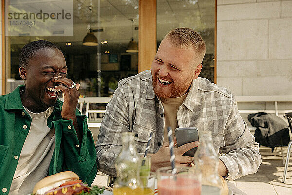 Glückliche multirassische Freunde  die zusammen in einem Straßencafé sitzen