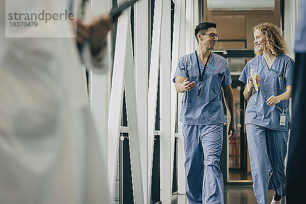 Lächelndes männliches und weibliches Gesundheitspersonal auf dem Korridor eines Krankenhauses