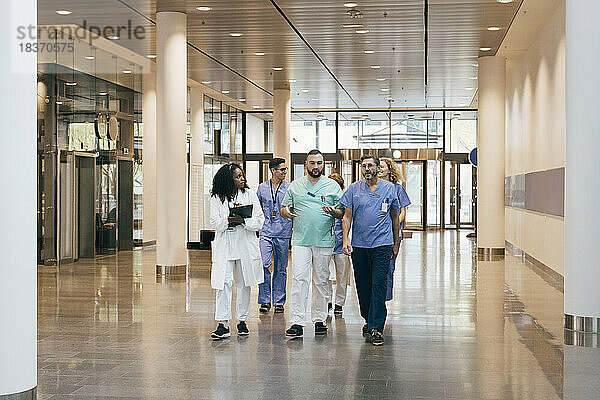Multirassische Gruppe von männlichen und weiblichen Krankenhausmitarbeitern  die sich in der Lobby unterhalten