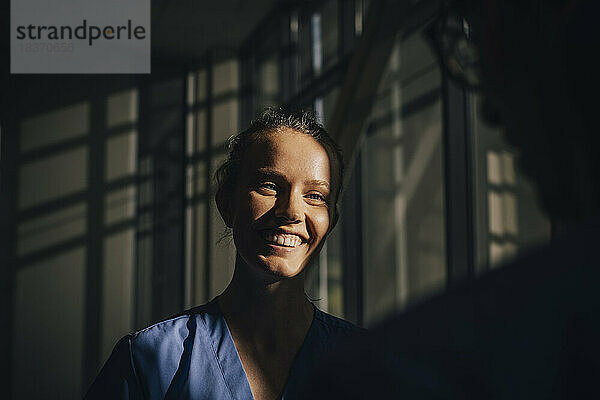 Sonnenlicht fällt auf das Gesicht einer glücklichen Krankenschwester im Krankenhaus
