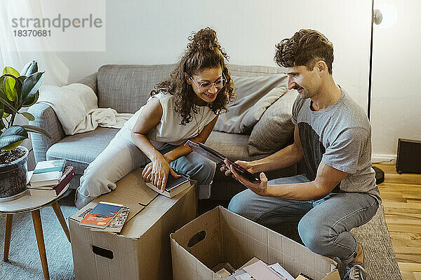 Mann teilt Fotorahmen mit Freundin beim Auspacken von Kartons zu Hause