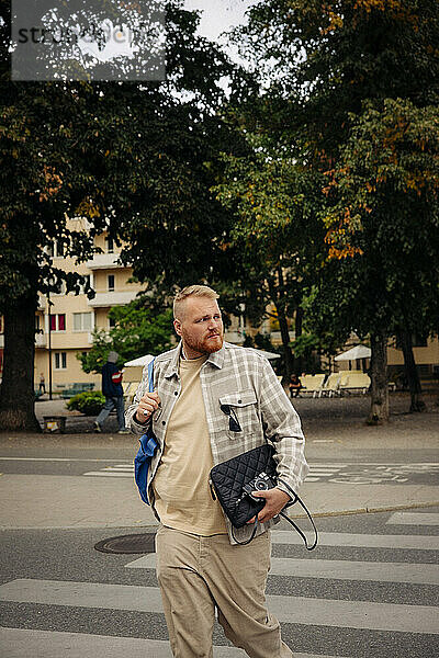 Übergewichtiger Mann schaut beim Überqueren der Straße in der Stadt weg