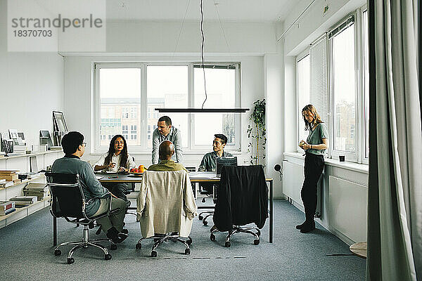 Männliche und weibliche Kollegen unterhalten sich während eines Geschäftstreffens im Büro miteinander