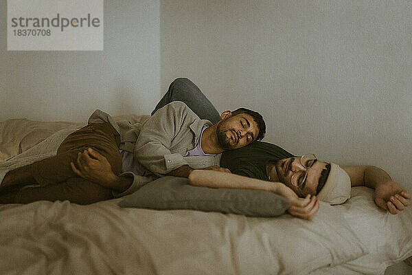 Mann entspannt sich mit seinem Freund  während er zu Hause auf dem Bett liegt