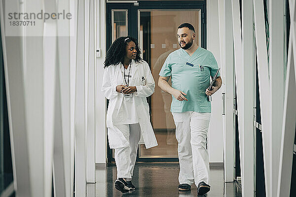 Männliches und weibliches Gesundheitspersonal im Gespräch auf dem Flur eines Krankenhauses