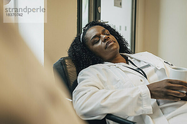 Müde Ärztin beim Nickerchen während der Kaffeepause im Krankenhaus