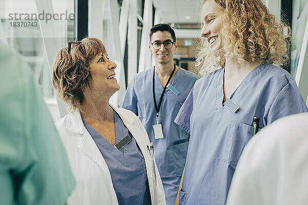 Glückliche weibliche Angestellte des Gesundheitswesens  die sich im Krankenhaus im Flur stehend anschauen