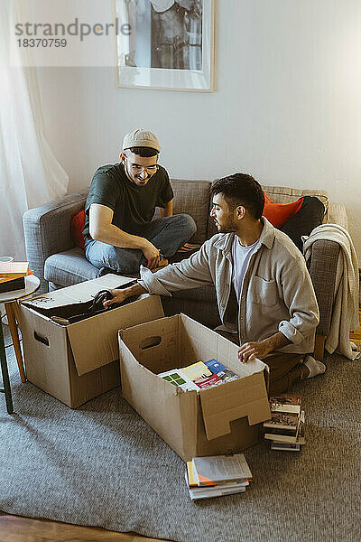 Schwules Paar  das sich beim Auspacken von Kartons zu Hause unterhält