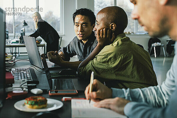 Multirassische Geschäftsleute diskutieren über Laptop bei der Arbeit im Büro