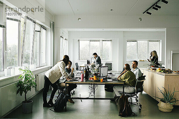 Geschäftskollegen  die am Schreibtisch sitzend im Büro diskutieren und planen