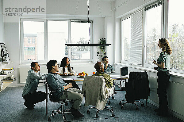 Geschäftsfrau beim Brainstorming mit männlichen und weiblichen Kollegen während einer Sitzung im Büro