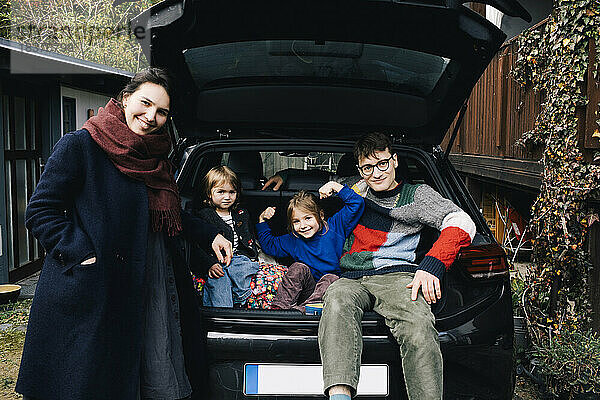 Glückliche Familie mit Elektroauto  die sich gemeinsam im Hinterhof vergnügt