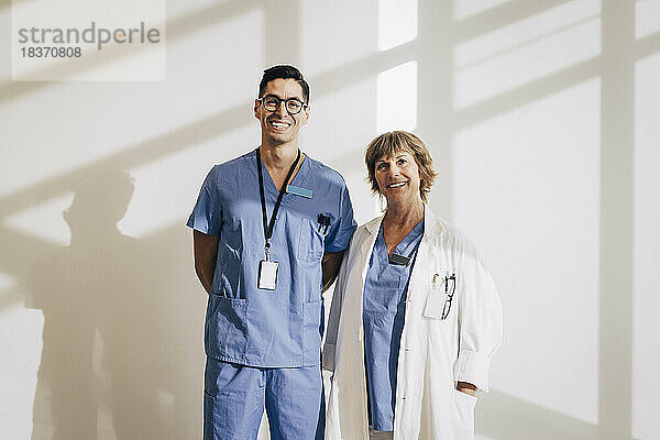 Porträt eines glücklichen Arztes  der mit einer Krankenschwester an der Wand eines Krankenhauses steht