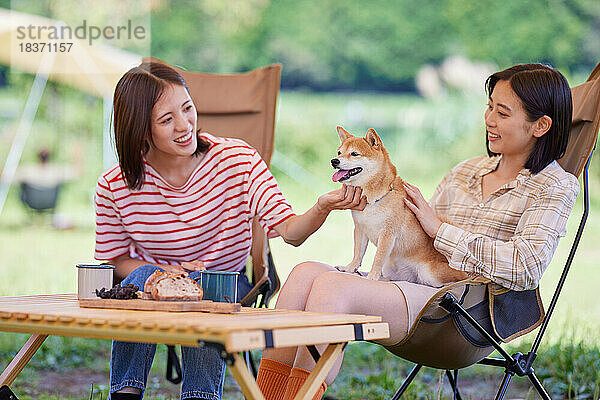 Junge japanische Frauen mit Hund auf dem Campingplatz