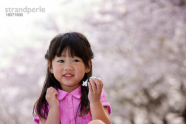 Japanisches Kinderporträt mit blühenden Kirschblüten