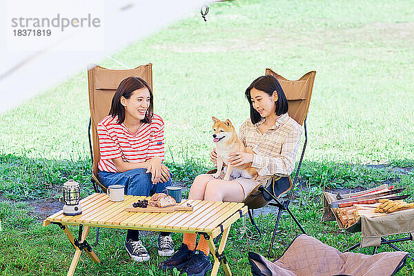 Junge japanische Frauen mit Hund auf dem Campingplatz