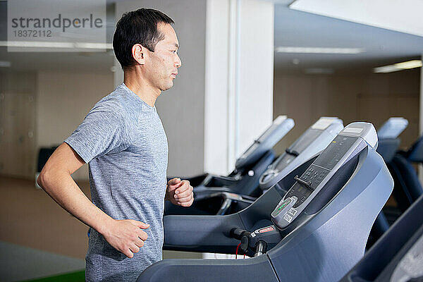 Japanischer Mann trainiert im Indoor-Fitnessstudio