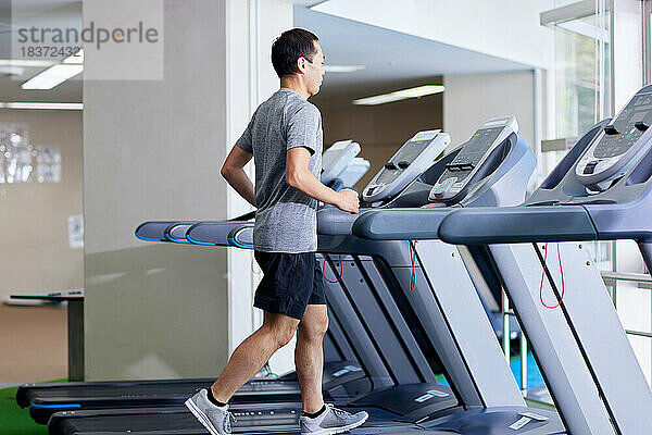 Japanischer Mann trainiert im Indoor-Fitnessstudio
