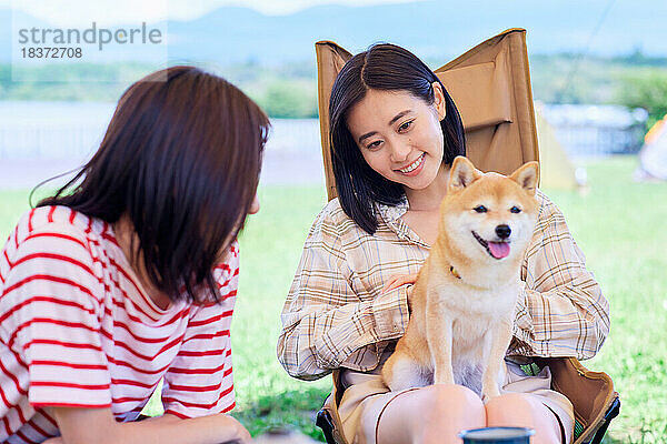 Junge japanische Frauen mit Hund auf dem Campingplatz