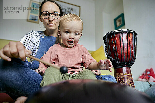 Mutter und Kleinkind spielen drinnen gemeinsam Musikinstrument