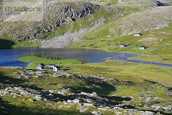 Grünes Land mit kargen  steinigen Bergen und einem See  einzelne Hütten  Gamvik  Arktis  Finnmark  Norwegen  Europa