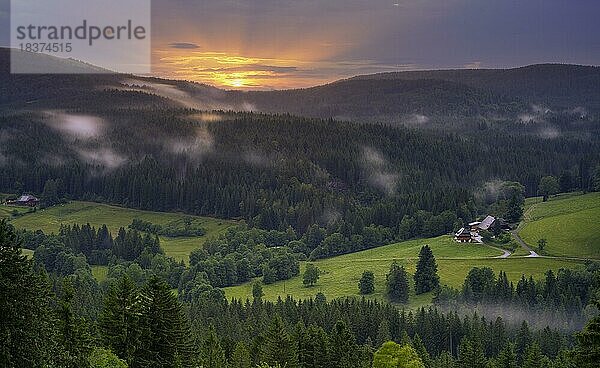 Einige Bauernhöfe  umgeben von Wiesen und Wald  abends nach einem Gewitter  mit einigen tiefen Wolken  bei Sonnenuntergang  Schwarzwald  Baden-Württemberg  Deutschland  Europa