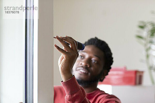 Junger Mann repariert Fenster mit Schraubenzieher zu Hause