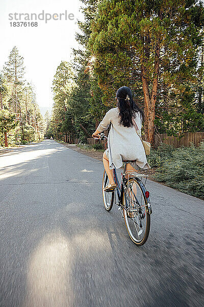 USA  Kalifornien  Tahoe City  Rückansicht einer Frau  die Fahrrad auf der Straße fährt