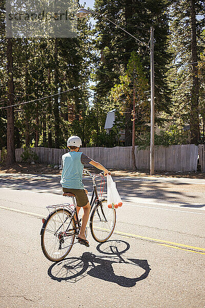 USA  Kalifornien  Tahoe City  Rückansicht eines Jungen (12-13)  der auf der Straße Fahrrad fährt