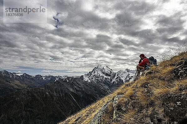 Bergsteiger auf herbstlicher Bergwiese mit Wolkenhimmel vor Gipfelmassiv des Ortler  Trafoier Tal  Meran  Vinschgau  Südtirol  Italien  Europa