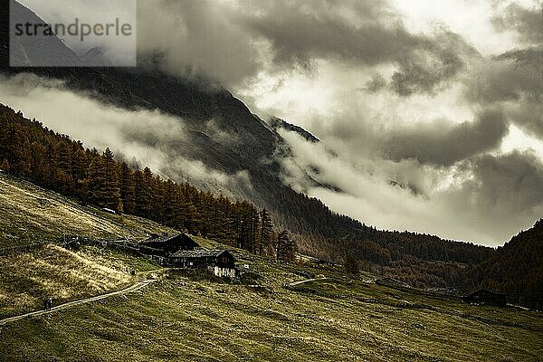 Almhütte in herbstlicher Berglandschaft mit bedrohlichem Wolkenhimmel  Pfossental  Meran  Vinschgau  Südtirol  Italien  Europa