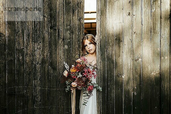 Schöne Braut mit einem Blumenstrauß mit Holztür Hintergrund als Hintergrund