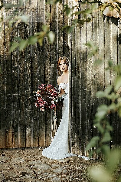 Schöne Braut mit einem Blumenstrauß mit Holztür Hintergrund als Hintergrund