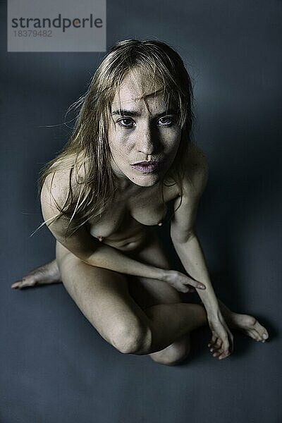 Junge  nackte Frau mit wildem  langen Haar hockt auf dem Boden  Portrait  Studioaufnahme  Köln  Nordrhein-Westfalen  Deutschland  Europa