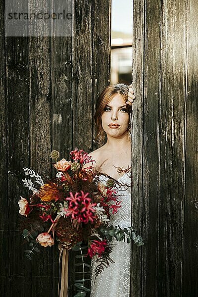 Schöne Braut mit einem Blumenstrauß mit Holztür Hintergrund als Hintergrund