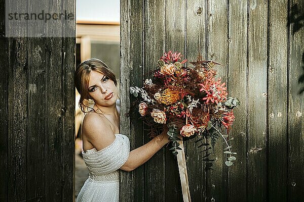 Schöne Braut mit einem Blumenstrauß mit Holztür Hintergrund als Hintergrund