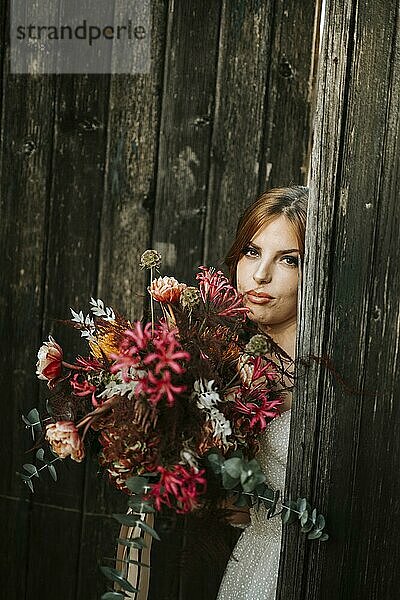 Schöne Braut mit einem Blumenstrauß mit Holztür Hintergrund als Hintergrund